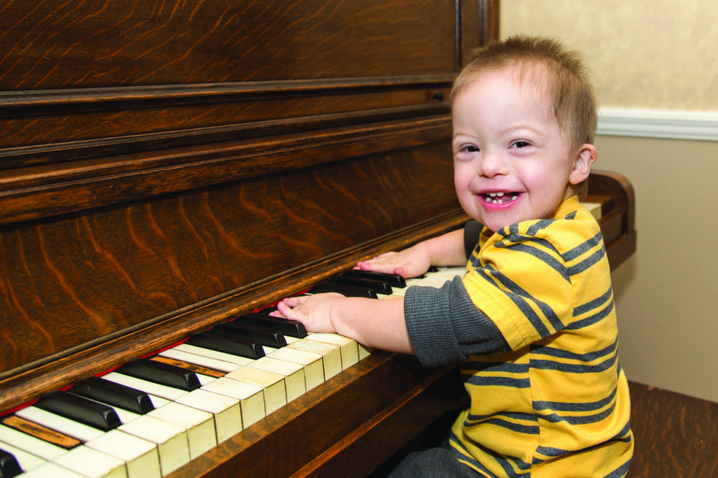 Laughing Down Syndrome boy playing on piano