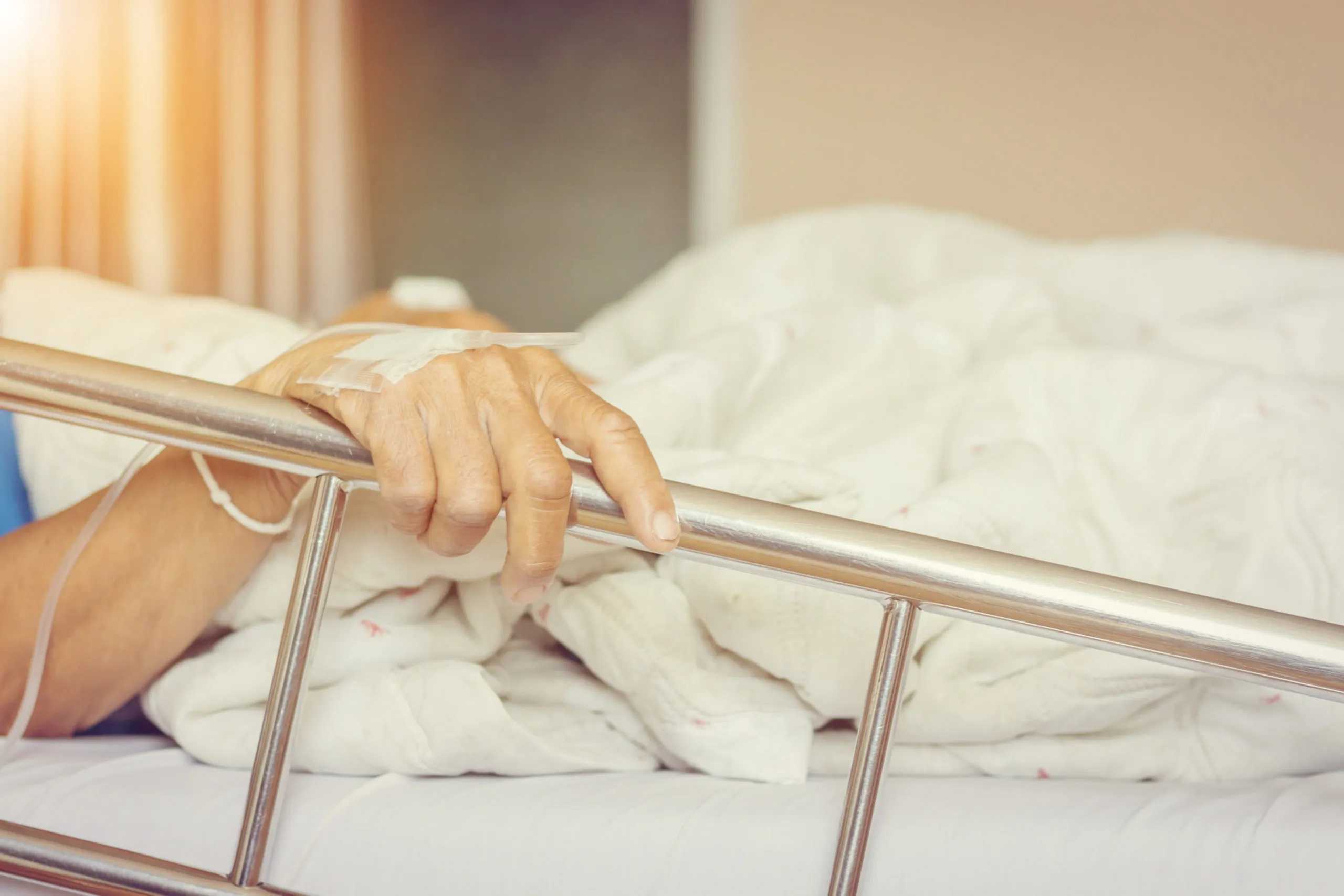 Close up of Asian elderly women patient's hand on a drip receiving a saline solution holding on to the bed in hospital