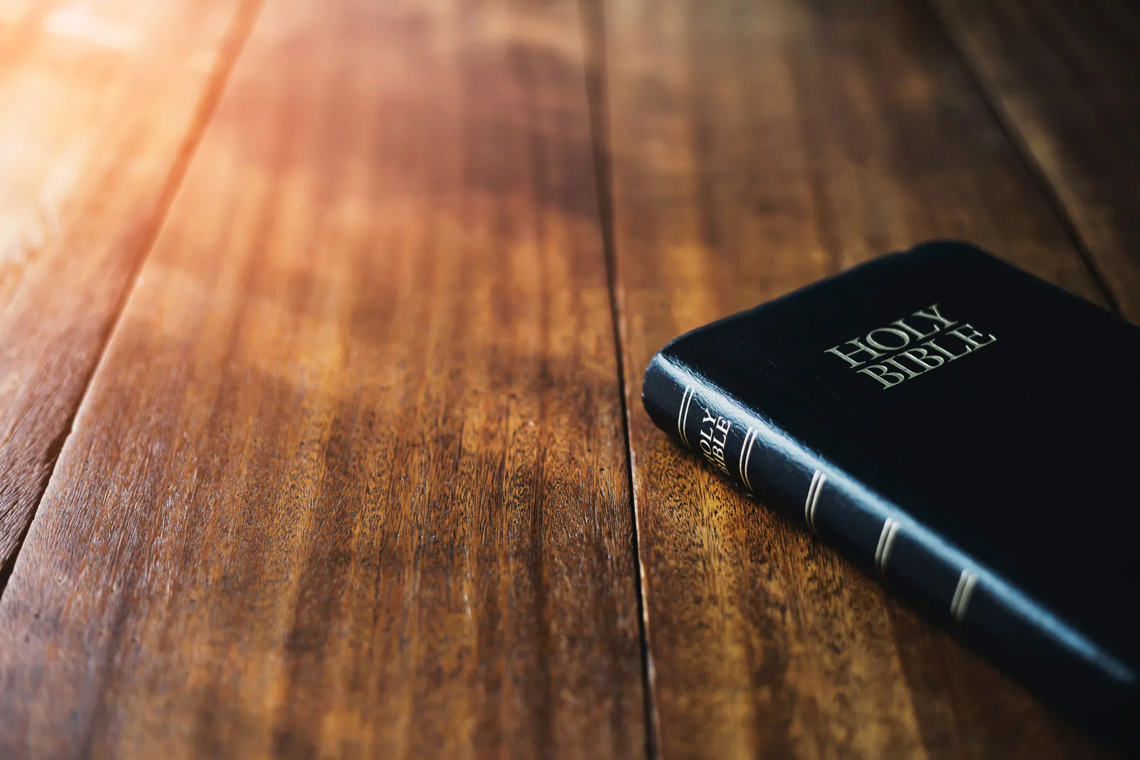 Holy Bible on wooden table background with soft morning sun light