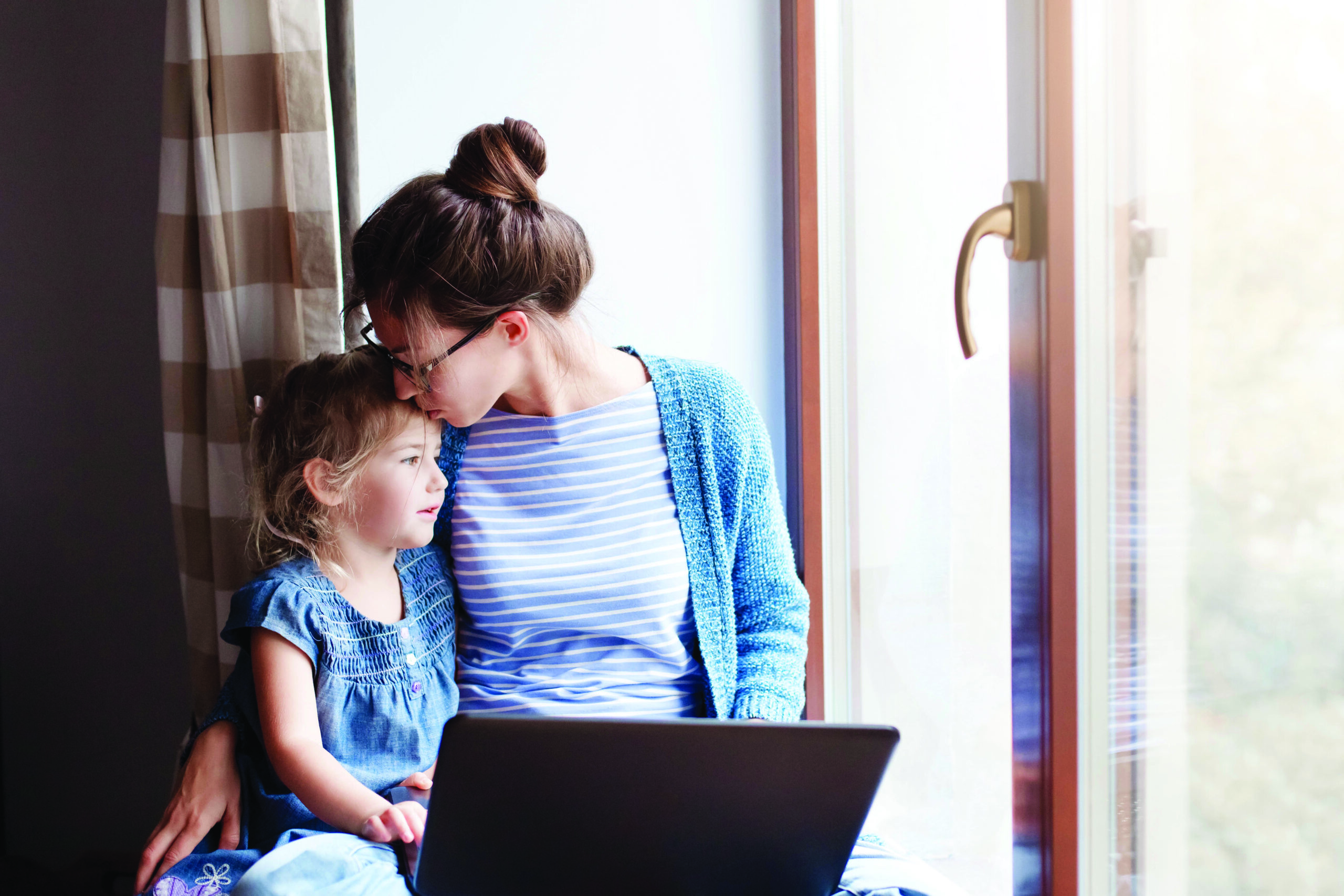 Mother hug and kiss daughter. Working mom works from home office.