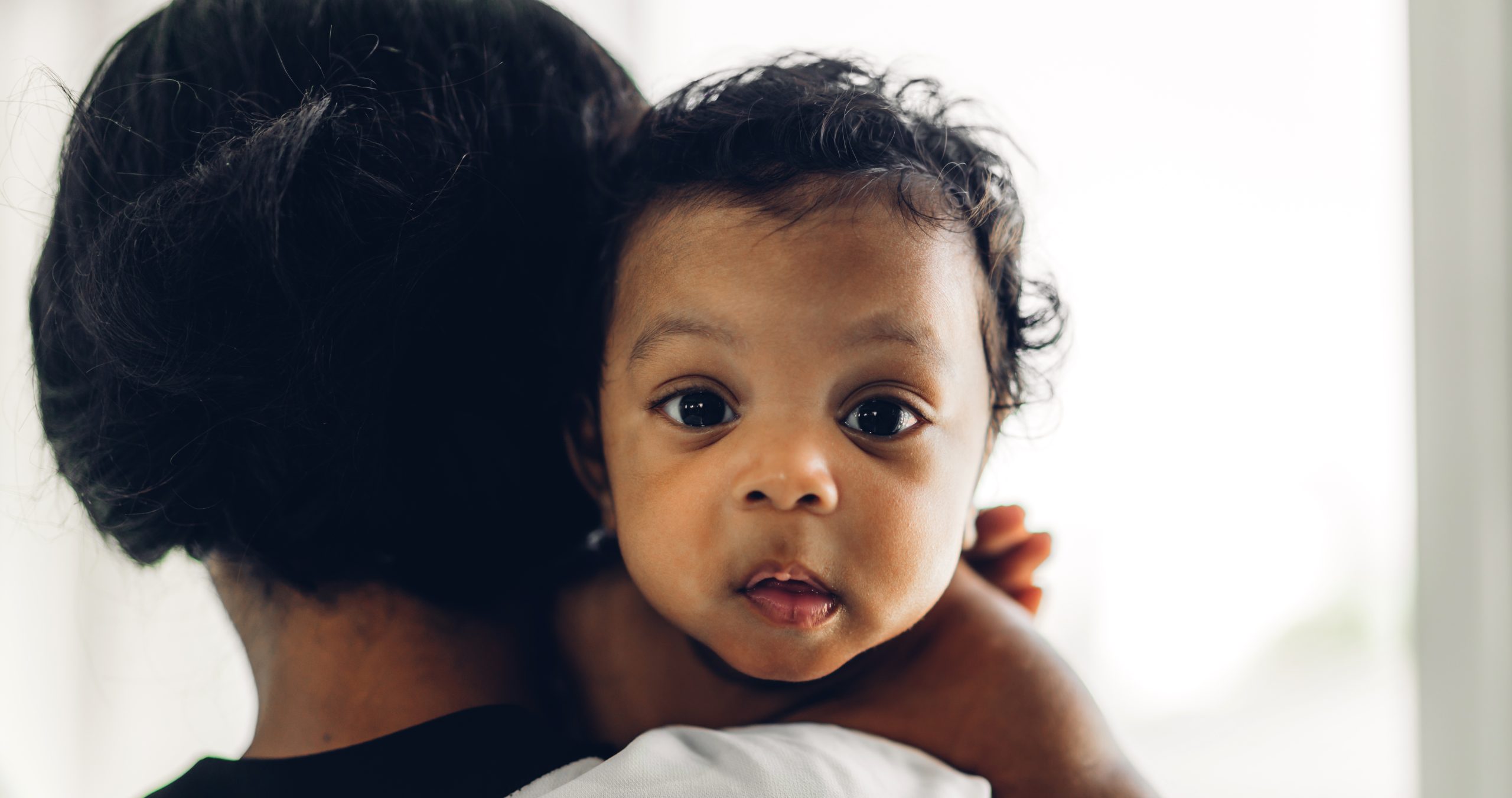 Portrait of enjoy happy love family african american mother playing with adorable little african american baby.Mom touching with cute son moments good time in a white bedroom.Love of black family