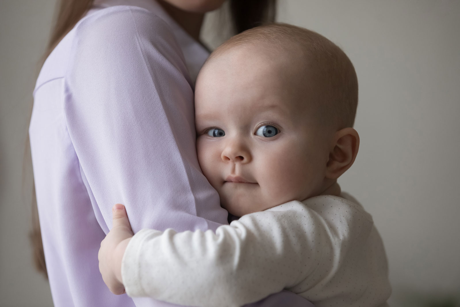 Close up head shot loving young woman cuddling sweet adorable small newborn baby toddler boy or girl with big grey eyes, expressing sincere feelings, enjoying tender moment, childhood and motherhood.